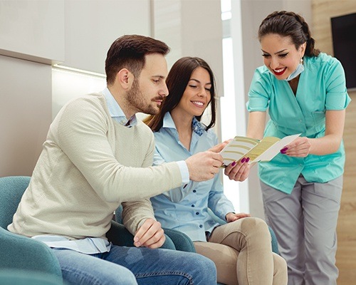 Smiling man and woman talking to dental team member