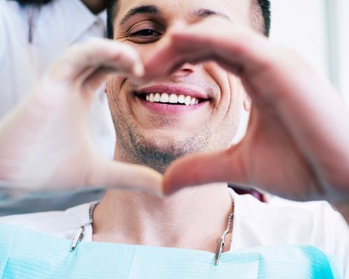 Patient and Center dentist make a heart with their hands 