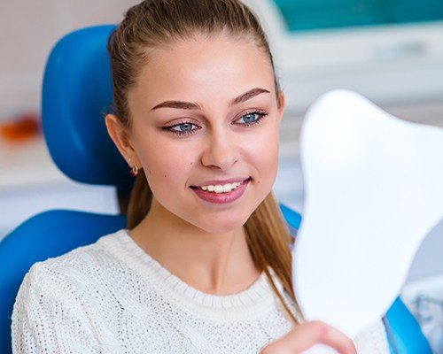 Young woman looking at her smile in the mirror