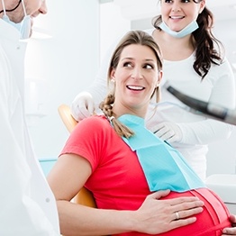 Pregnant woman in dental chair talking to her dentist