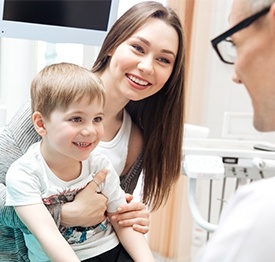 Mother holding her young child in her lap at dental office