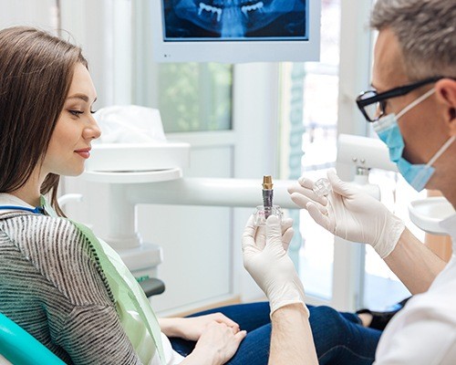 Dentist showing patient dental implant model