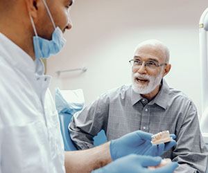 Dentist talking to old man about cost of dentures in Center