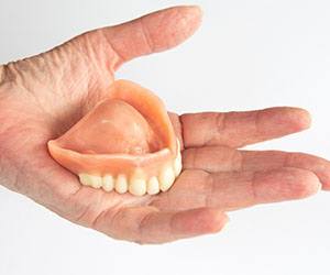 Hand holding full denture on white background 