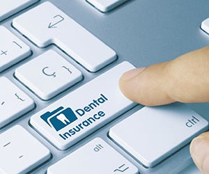 Finger pointing to dental insurance button on keyboard