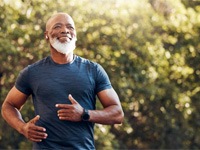 mature man jogging on a trail and smiling