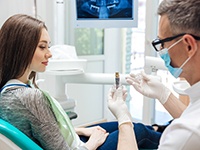 A dentist showing his patient a dental implant