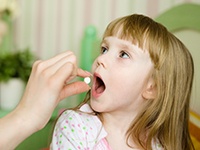 Parent giving child pill before dentist’s appointment