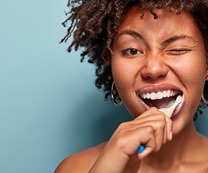 Woman brushing her teeth to prevent dental emergencies in Center