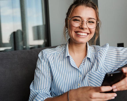 Woman smiling with phone after root canal therapy in Center, TX