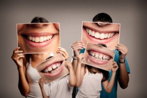 family holding up pictures of their smiles