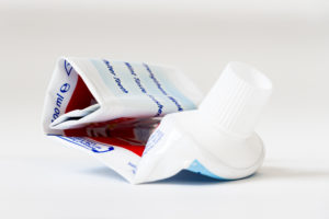 empty, rolled up tube of toothpaste on white background