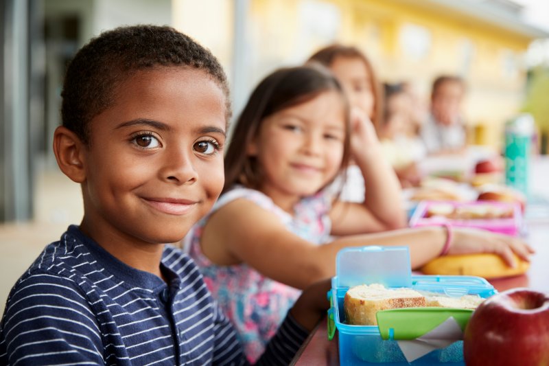 young boy smiling while eating school lunch