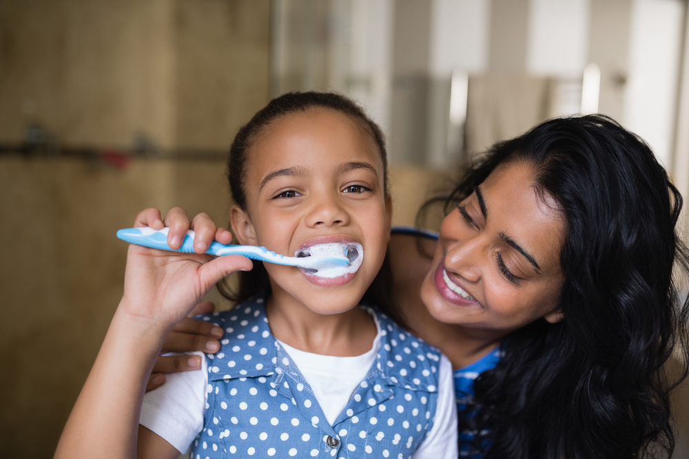 parent helping child use toothbrush