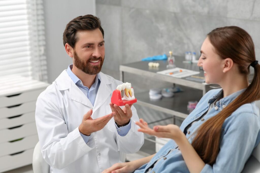 A dentist showing a patient a model of a dental implant in the jaw.