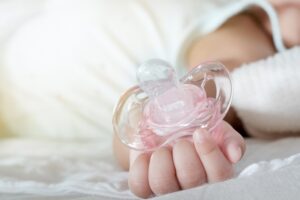 Baby holding pacifier. 