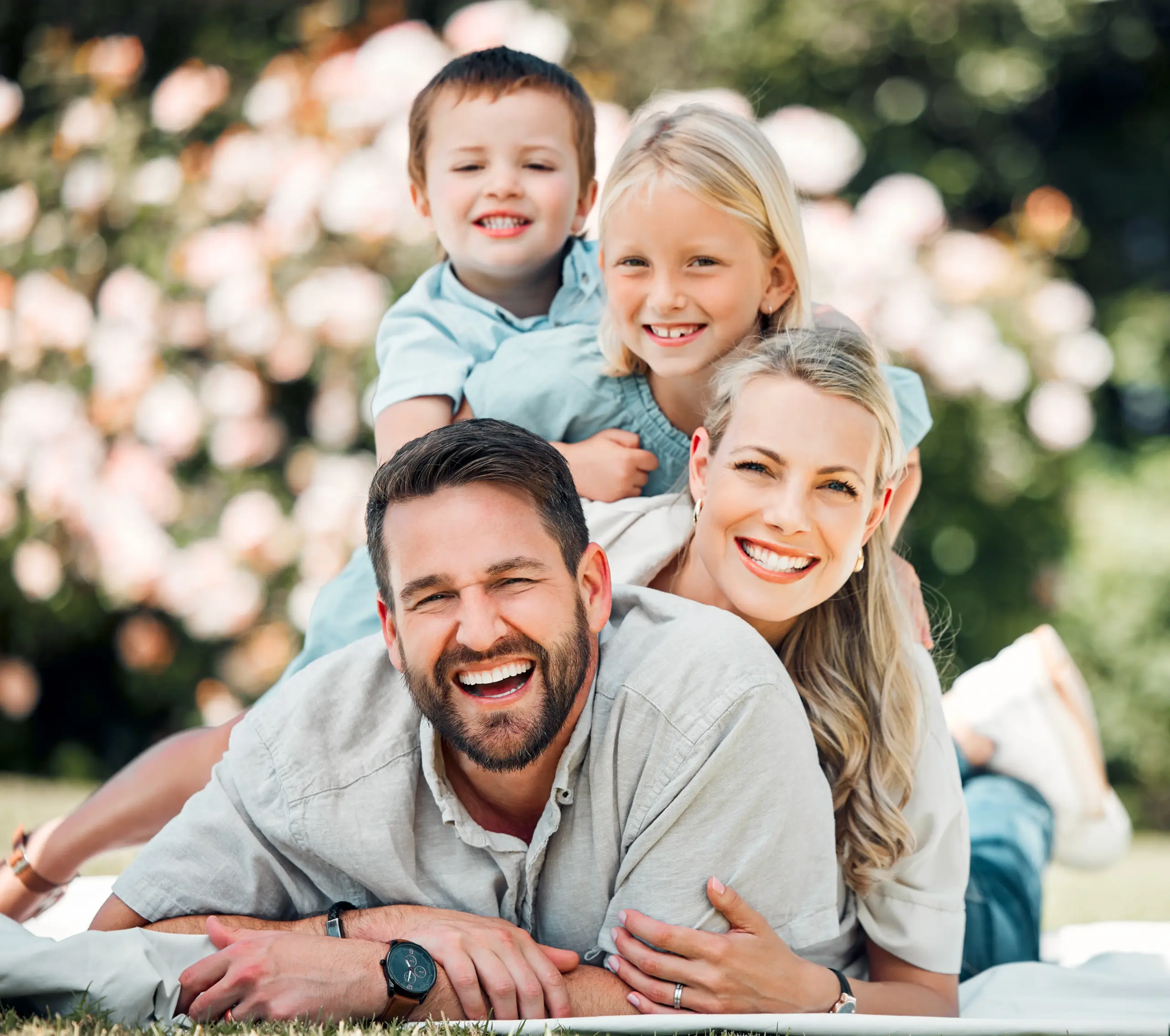 Happy family lying on grass smiling with healthy teeth in Center TX